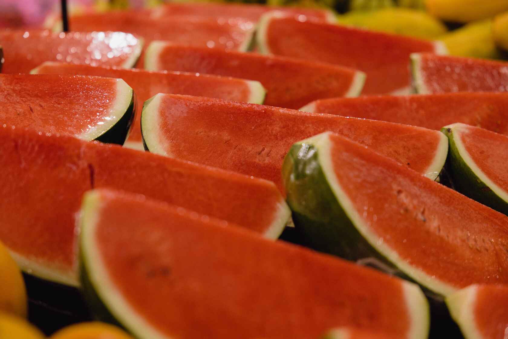 In-store photo: quarters of bright red watermelon pieces on a stand